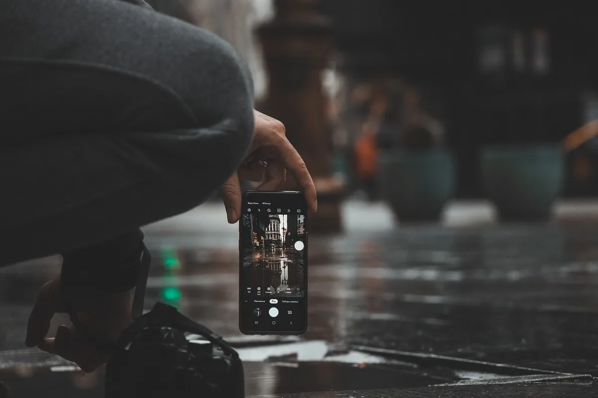 Close-up of anonymous hands holding a smartphone with a smoking-cessation coaching screen, a coffee cup on the side, daylight through a window