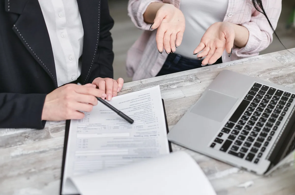 Hands filling an online insurance sign-up form on a laptop, a policy page visible but unreadable